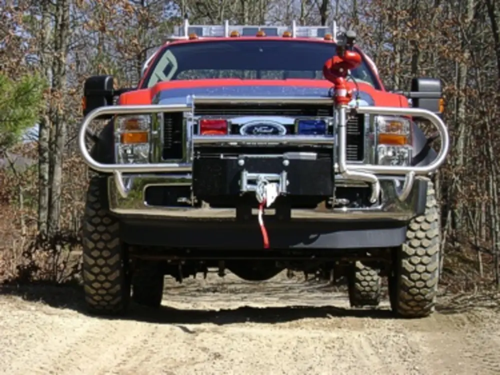 Exterior view of small fire truck showing cab, body compartments, and wheel/tire area.