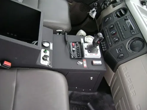 Exterior view of small fire truck showing cab, body compartments, and wheel/tire area.