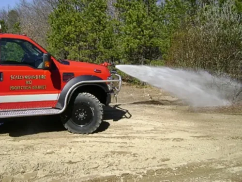 Exterior view of small fire truck showing cab, body compartments, and wheel/tire area.