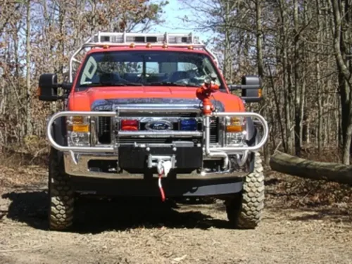 Exterior view of small fire truck showing cab, body compartments, and wheel/tire area.