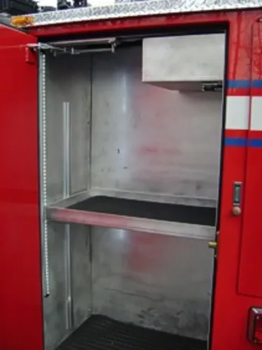 Exterior view of small fire truck showing cab, body compartments, and wheel/tire area.