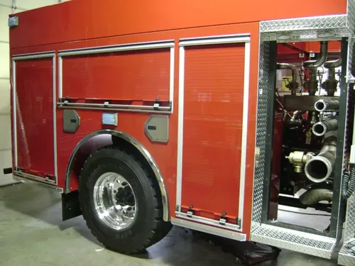 Exterior view of small fire truck showing cab, body compartments, and wheel/tire area.