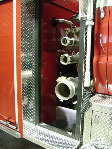 Exterior view of small fire truck showing cab, body compartments, and wheel/tire area.