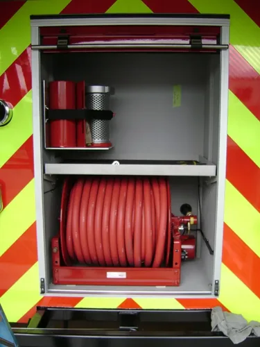Exterior view of small fire truck showing cab, body compartments, and wheel/tire area.