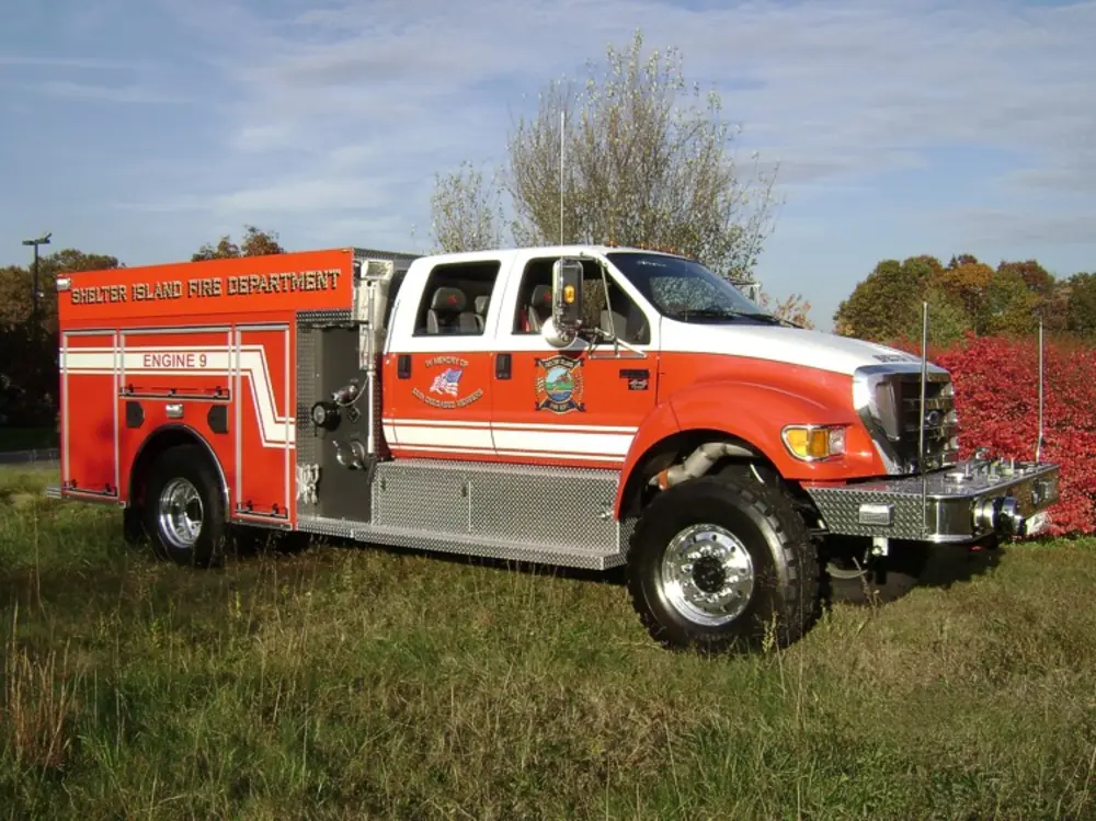 Exterior view of small fire truck showing cab, body compartments, and wheel/tire area.
