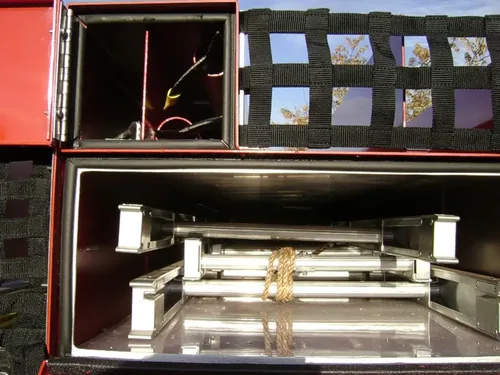 Exterior view of small fire truck showing cab, body compartments, and wheel/tire area.