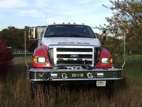Exterior view of small fire truck showing cab, body compartments, and wheel/tire area.