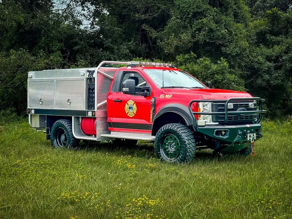 Front-left three-quarter exterior view of red brush truck with utility body.