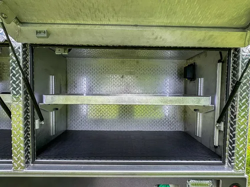 Wide side compartment interior with dual shelves and lighting.