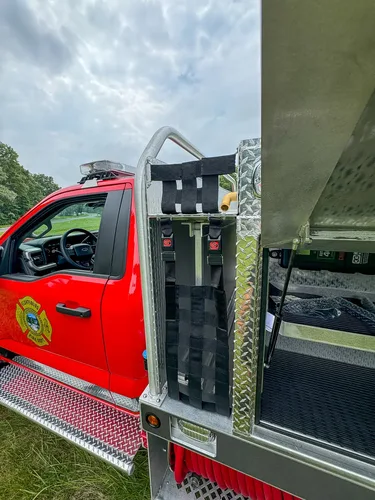 Vertical equipment rack behind cab with mounted red packs and straps.