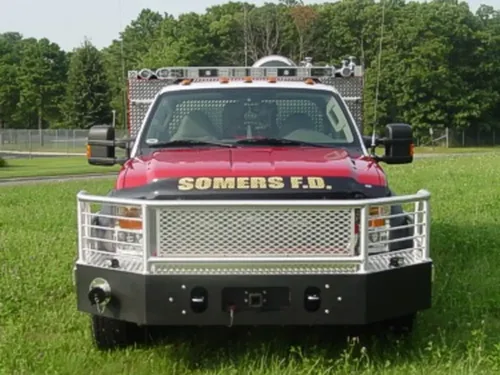 Exterior view of small fire truck showing cab, body compartments, and wheel/tire area.