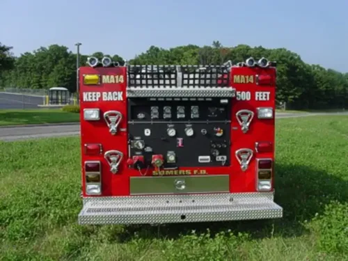 Exterior view of small fire truck showing cab, body compartments, and wheel/tire area.