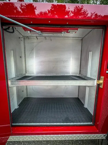 Compartment interior close-up with shelf and ribbed floor mat.