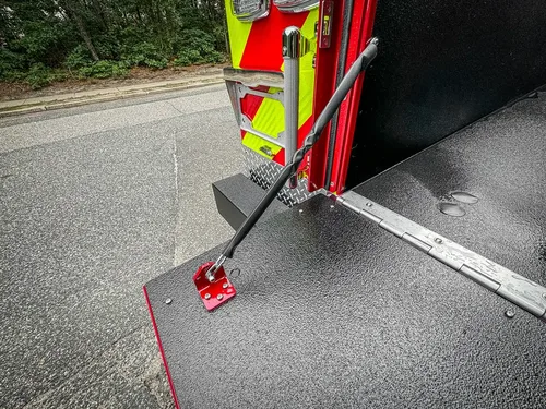 Tailgate hinge and support bracket close-up at right corner.