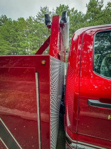 Cab-to-body junction close-up with red panel and diamond-plate corner.