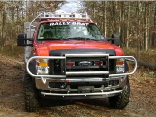 Exterior view of small fire truck showing cab, body compartments, and wheel/tire area.