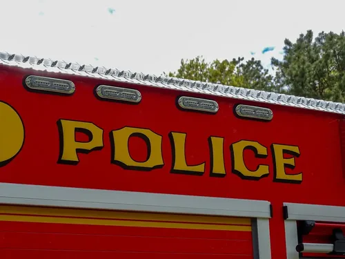 Exterior view of small fire truck showing cab, body compartments, and wheel/tire area.