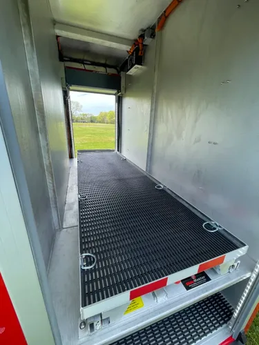 Exterior view of small fire truck showing cab, body compartments, and wheel/tire area.