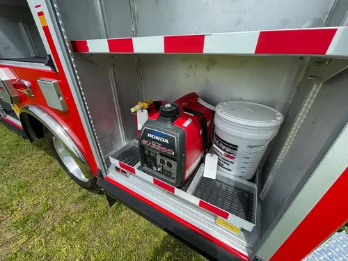 Exterior view of small fire truck showing cab, body compartments, and wheel/tire area.