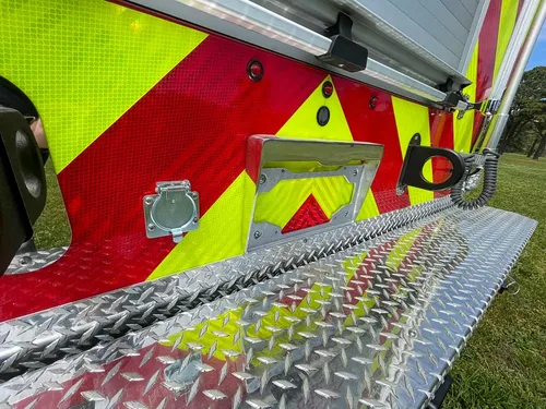 Exterior view of small fire truck showing cab, body compartments, and wheel/tire area.