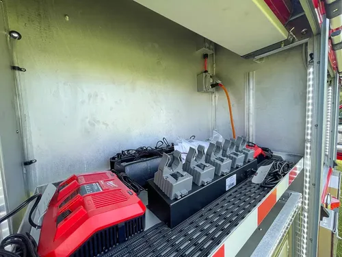 Exterior view of small fire truck showing cab, body compartments, and wheel/tire area.