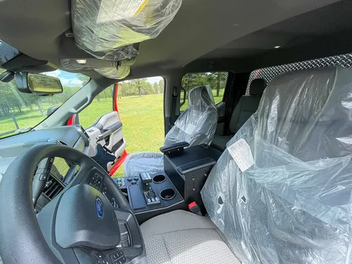 Exterior view of small fire truck showing cab, body compartments, and wheel/tire area.