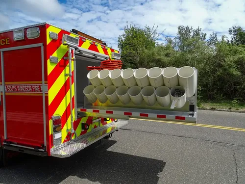 Exterior view of small fire truck showing cab, body compartments, and wheel/tire area.