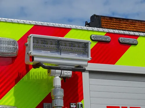 Exterior view of small fire truck showing cab, body compartments, and wheel/tire area.