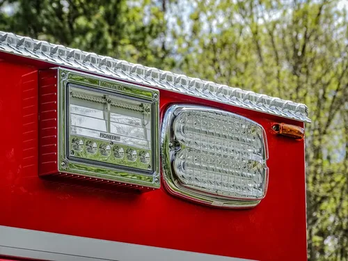 Exterior view of small fire truck showing cab, body compartments, and wheel/tire area.