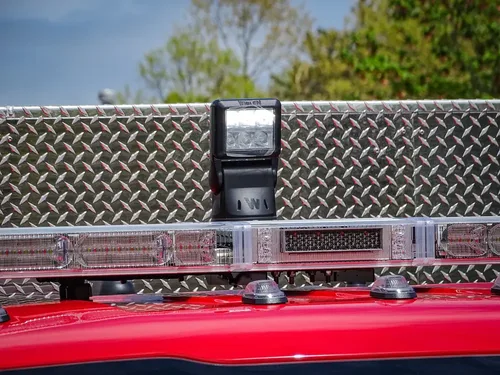 Exterior view of small fire truck showing cab, body compartments, and wheel/tire area.