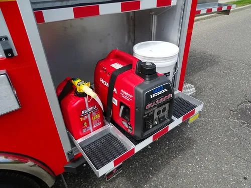 Exterior view of small fire truck showing cab, body compartments, and wheel/tire area.