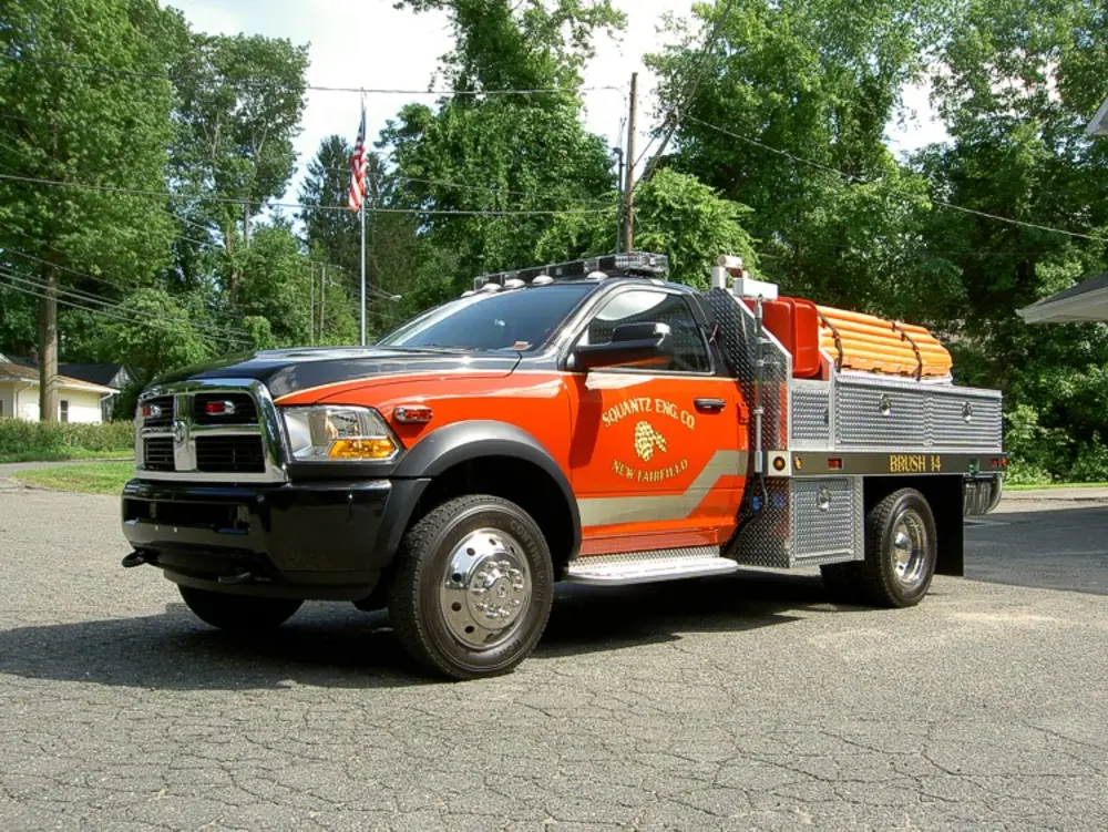 Exterior view of small fire truck showing cab, body compartments, and wheel/tire area.