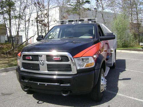 Exterior view of small fire truck showing cab, body compartments, and wheel/tire area.
