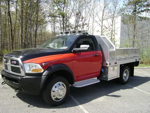 Exterior view of small fire truck showing cab, body compartments, and wheel/tire area.