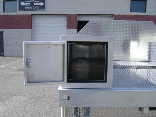 Exterior view of small fire truck showing cab, body compartments, and wheel/tire area.