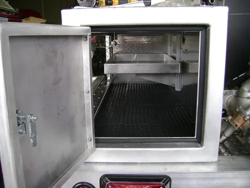 Exterior view of small fire truck showing cab, body compartments, and wheel/tire area.