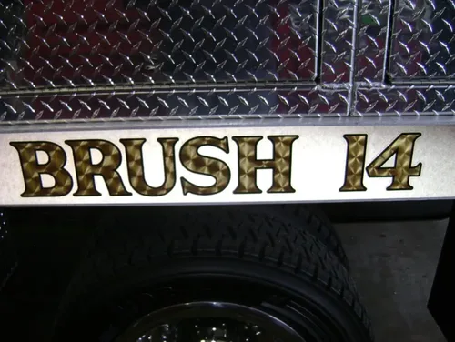 Exterior view of small fire truck showing cab, body compartments, and wheel/tire area.