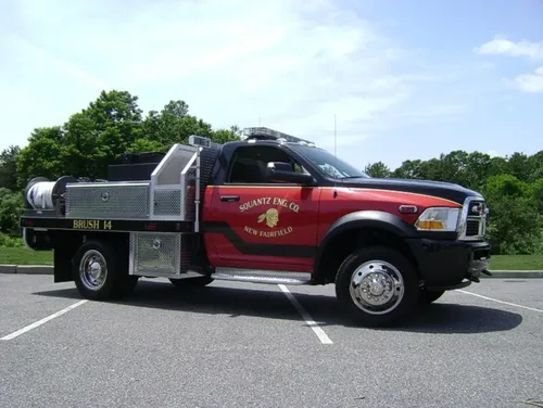 Exterior view of small fire truck showing cab, body compartments, and wheel/tire area.