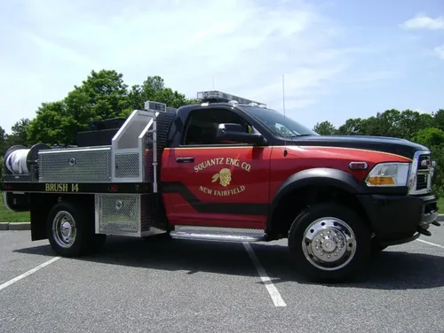 Exterior view of small fire truck showing cab, body compartments, and wheel/tire area.