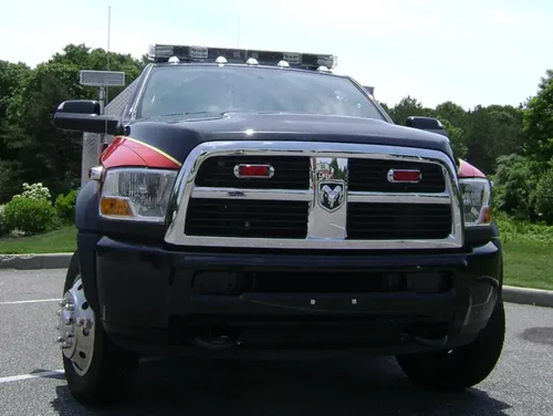 Exterior view of small fire truck showing cab, body compartments, and wheel/tire area.