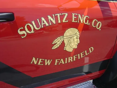 Exterior view of small fire truck showing cab, body compartments, and wheel/tire area.