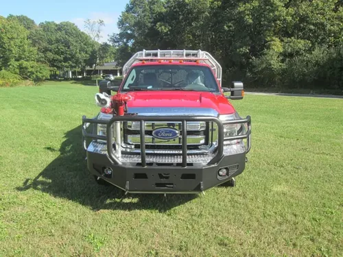 Exterior view of small fire truck showing cab, body compartments, and wheel/tire area.