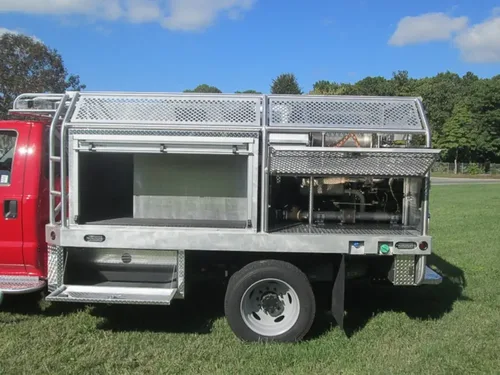 Exterior view of small fire truck showing cab, body compartments, and wheel/tire area.