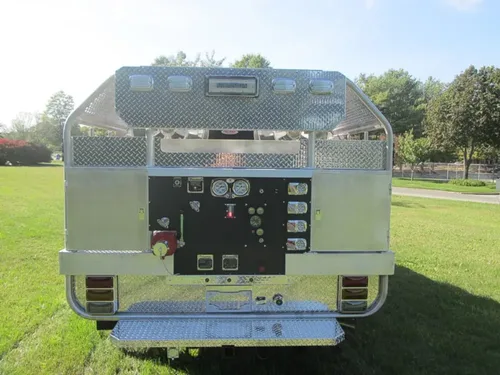 Exterior view of small fire truck showing cab, body compartments, and wheel/tire area.