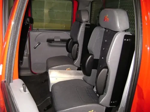 Exterior view of small fire truck showing cab, body compartments, and wheel/tire area.