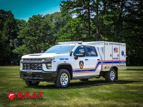 Exterior view of small fire truck showing cab, body compartments, and wheel/tire area.