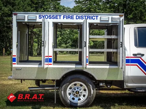 Exterior view of small fire truck showing cab, body compartments, and wheel/tire area.