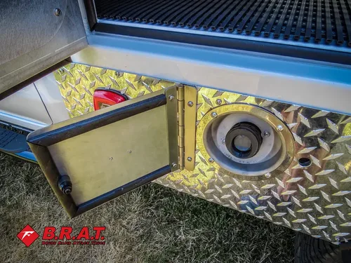 Exterior view of small fire truck showing cab, body compartments, and wheel/tire area.