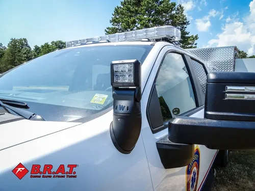 Exterior view of small fire truck showing cab, body compartments, and wheel/tire area.