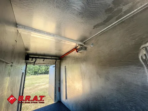 Exterior view of small fire truck showing cab, body compartments, and wheel/tire area.